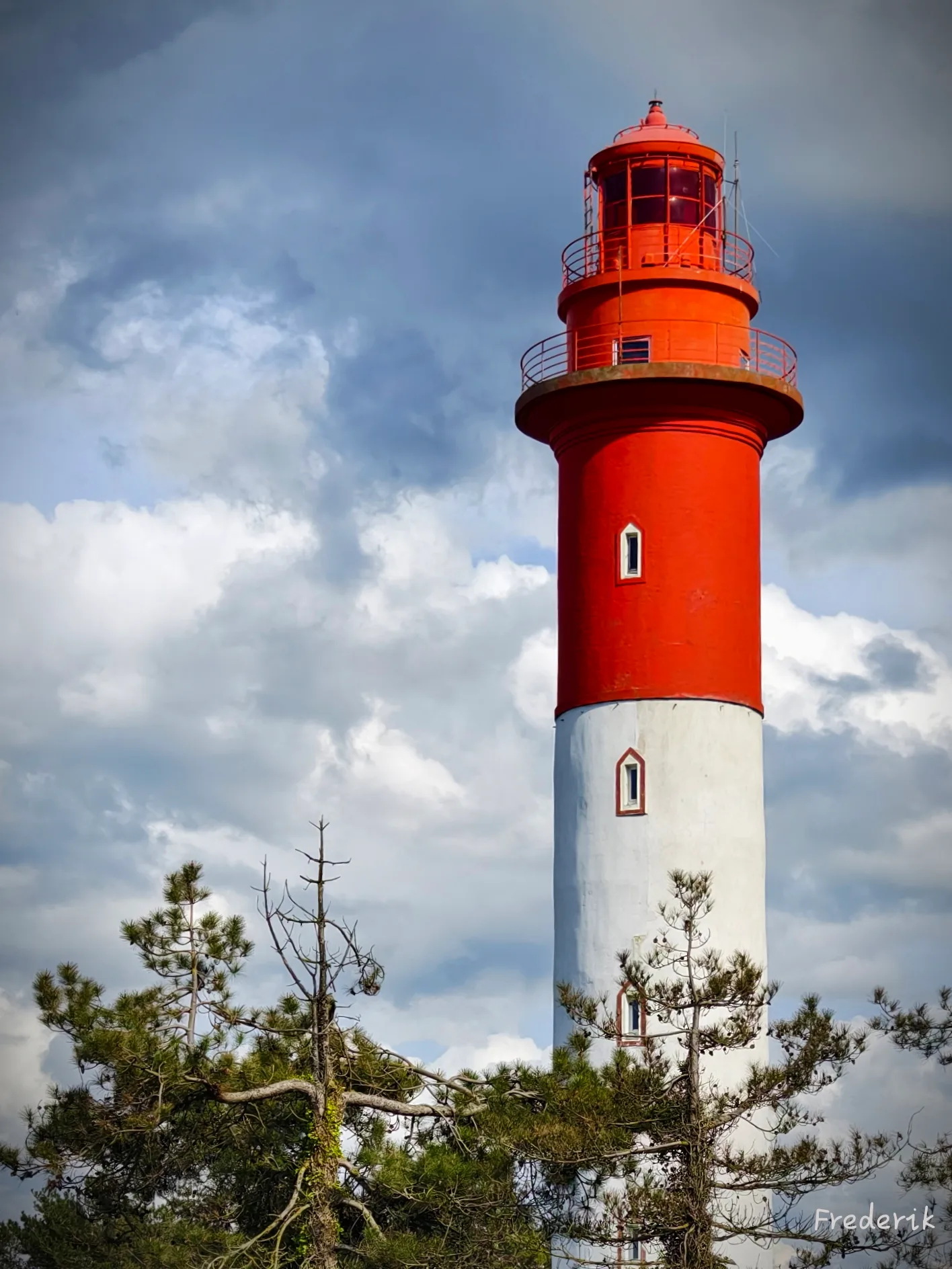 Phare rouge et blanc sous un ciel nuageux